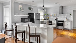 A modern kitchen with a marble island, white cabinetry, and stainless steel appliances. - 49th Terrace Haven (Birmingham)