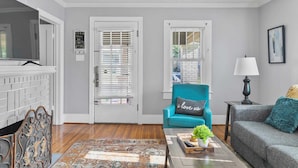 A living room with a fireplace, a teal armchair, a grey sofa, and a coffee table with a plant. - 49th Terrace Haven (Birmingham)