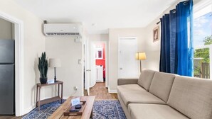 Uma sala de estar com um sofá bege, uma mesa de centro de madeira e um tapete azul estampado.