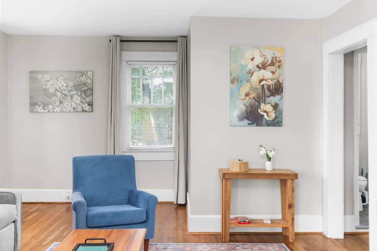 Un salón con un sillón azul, una mesa de centro de madera y dos cuadros en la pared.