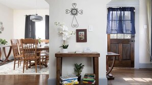 Een eethoek met houten stoelen en een tafel, een decoratief object aan de muur, en een deur met gordijn.