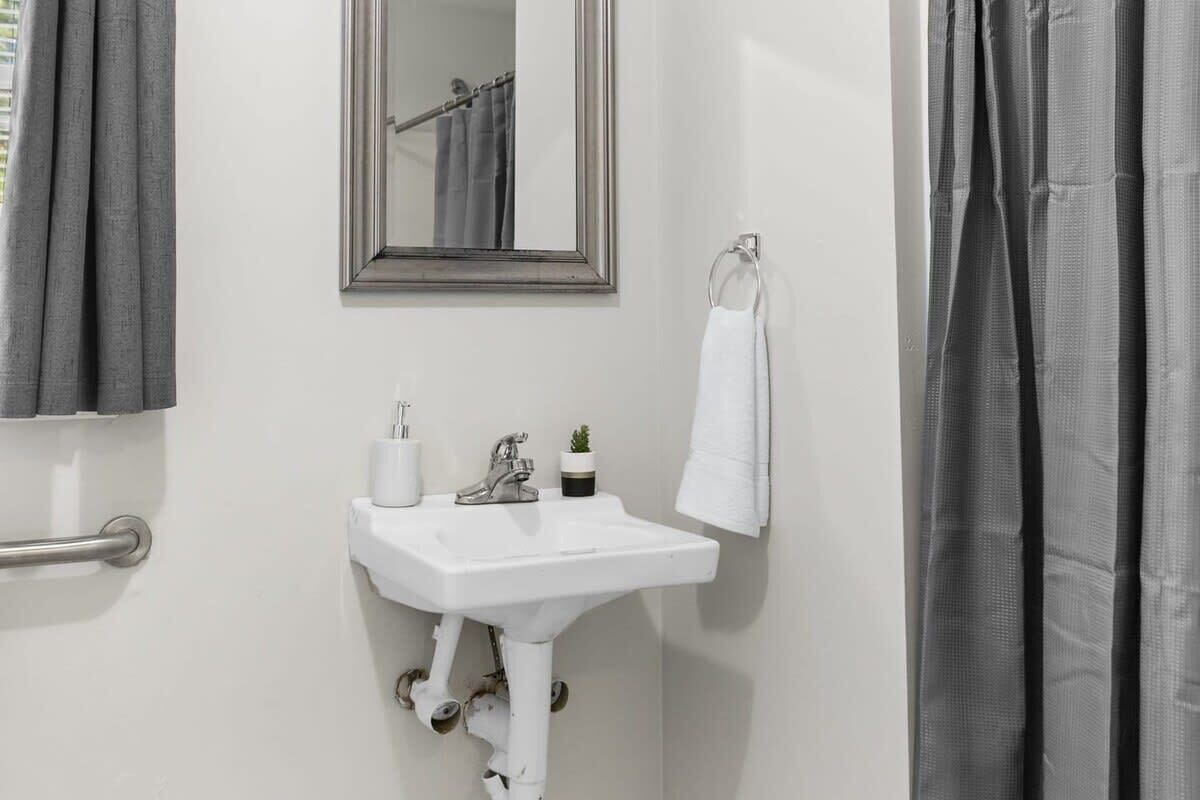 A bathroom with a white sink, a mirror, a towel rack, and a shower curtain.