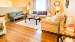 Ein Wohnzimmer mit einer Couch, einem Couchtisch, einem Deckenventilator und einem Fenster mit Vorhängen.