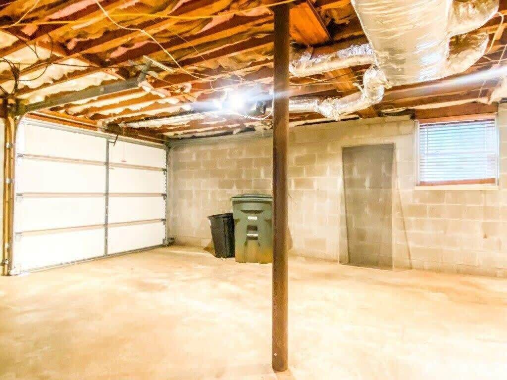 Een garage met een betonnen vloer, een houten plafond en een garagepoort.