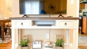 Eine weiße Unterhaltungseinheit mit einem Flachbildfernseher, zwei Schubladen und einem Wi-Fi-Symbol.