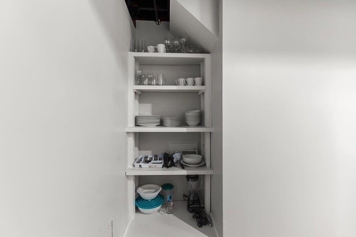 A white, multi-tiered shelving unit with various kitchenware items.