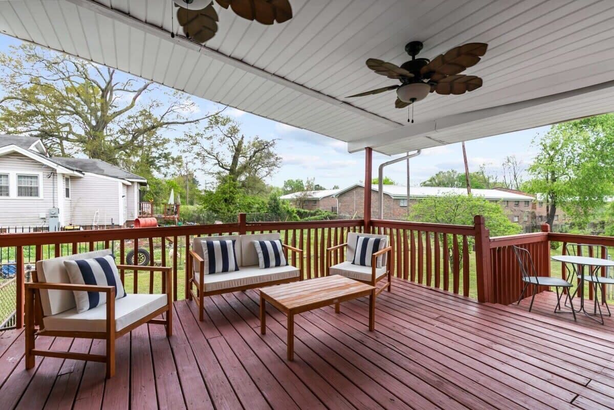 A covered deck with wooden furniture, a ceiling fan, and a view of neighboring houses.