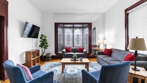 A modern living room with a sofa set, a coffee table, and a television mounted on the wall.