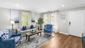 Un salon comprenant un canapé, deux fauteuils, une table basse et un tapis.