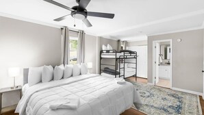 Une chambre à coucher comprenant un lit, un ventilateur de plafond, un lit superposé, une table de chevet et un tapis.