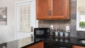 A kitchen with wooden cabinets, a microwave, and a dishwasher. - Highland Drive Hideaway (Birmingham)
