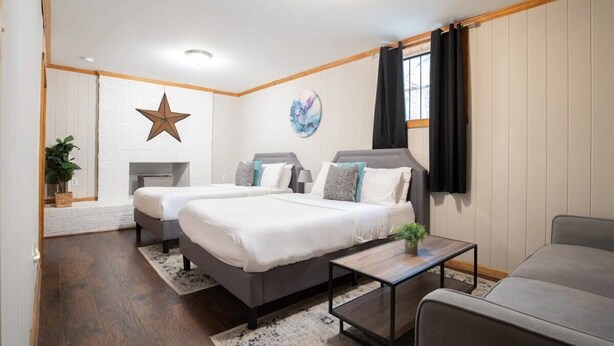 A modern hotel room with two beds, a sofa, a coffee table, and a star decoration on the wall. - Highland Drive Hideaway (Birmingham)