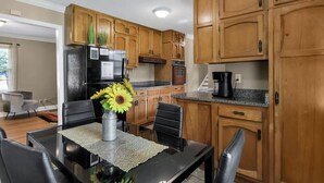 Una cucina moderna con mobili in legno, un frigorifero nero e un'area pranzo con tavolo e sedie.