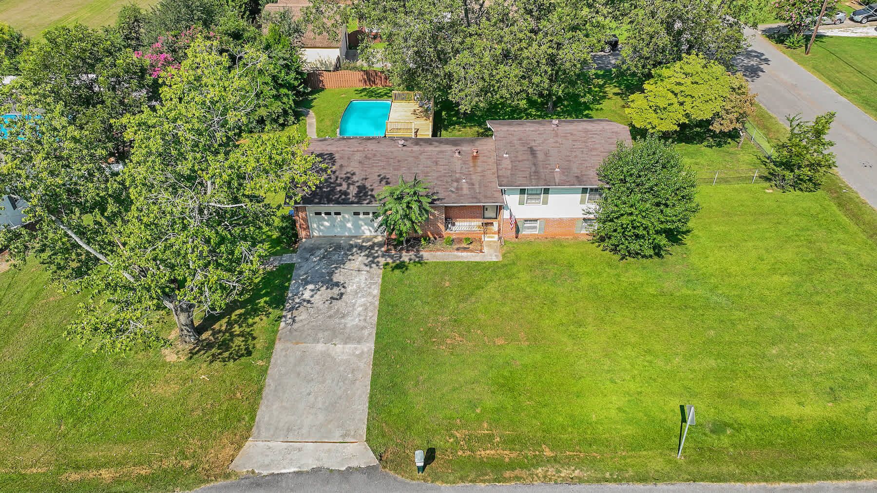 Vista aérea de una propiedad residencial con piscina, garaje independiente y césped bien cuidado.