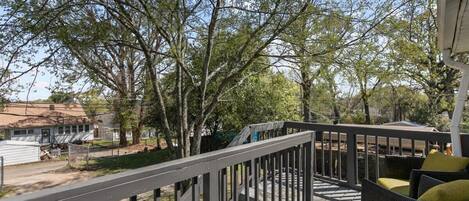 A wooden deck with a railing, surrounded by trees.