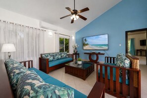 A living room with a sofa, coffee table, TV, and a ceiling fan.