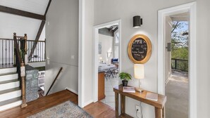 A staircase with wooden railings and a stone accent wall, leading to a dining area with a table and chairs. - Observatory Drive Terrace House (Birmingham)