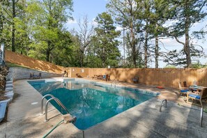 Ein rechteckiger Swimmingpool mit Holzterrasse und Liegestühlen.