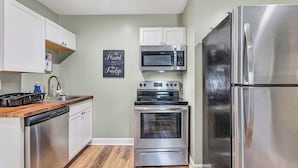 A modern kitchen with stainless steel appliances, white cabinetry, and a wooden countertop. - Bethany B Huntsville Oasis (Huntsville)