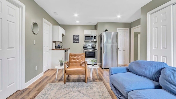 A compact living space with a kitchenette, a blue sofa, a patterned rug, and a leather chair. - Bethany B Huntsville Oasis (Huntsville)