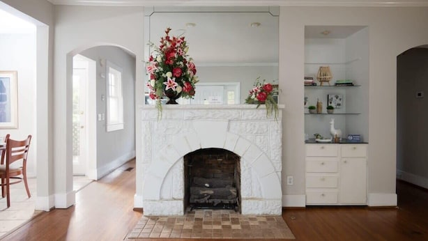 A living room with a white fireplace, a wooden floor, and a dining area with a chair. - Arlington Crescent Revival - Unit 1 (Birmingham)