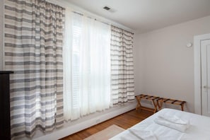 A room with a bed, a wooden bench, and a window with striped curtains. - Arlington Crescent Revival - Unit 1 (Birmingham)