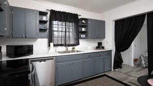 A compact kitchen with grey cabinets, a black microwave, and a dishwasher. - 4th St Little Blue in Bham (Birmingham)