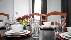 A dining table set with white bowls, plates, and clear glasses, with a red and white patterned table runner. - 4th St Little Blue in Bham (Birmingham)