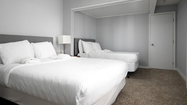 A hotel room with two beds, a desk, and a door. - 4th St Little Blue in Bham (Birmingham)