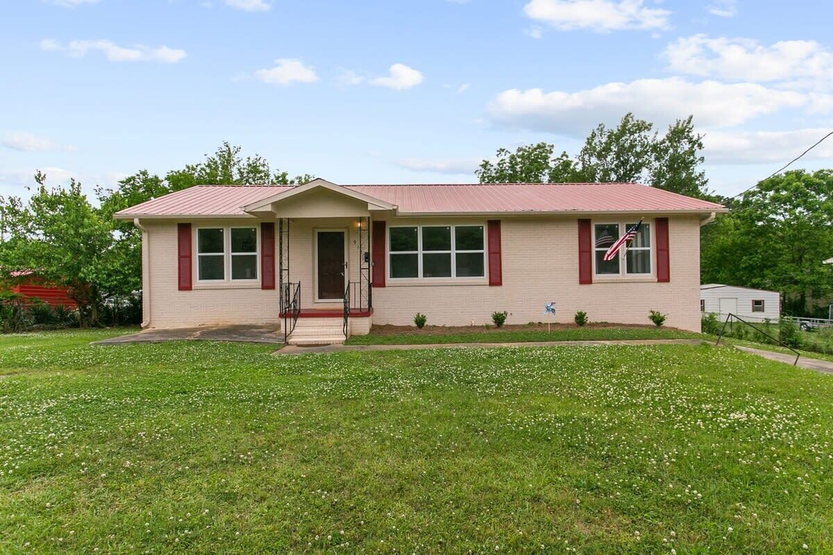 A two-story house with a red roof, beige walls, and a small front porch.