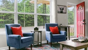 A room with two blue armchairs, a small table, and a red door. - Dugan Ave Both (Birmingham)