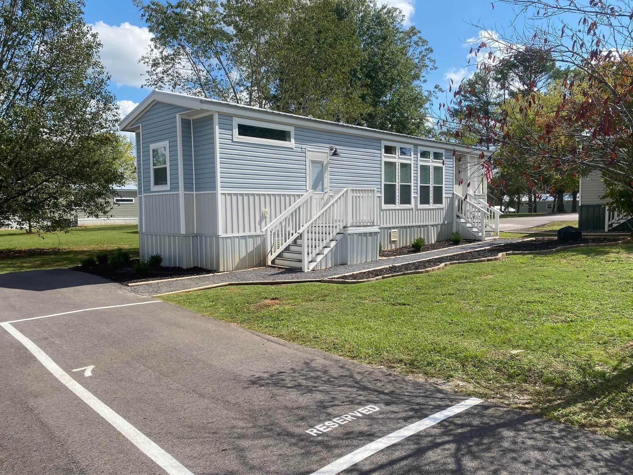 A small, single-story building with a white exterior, a front porch, and a staircase leading to the entrance.