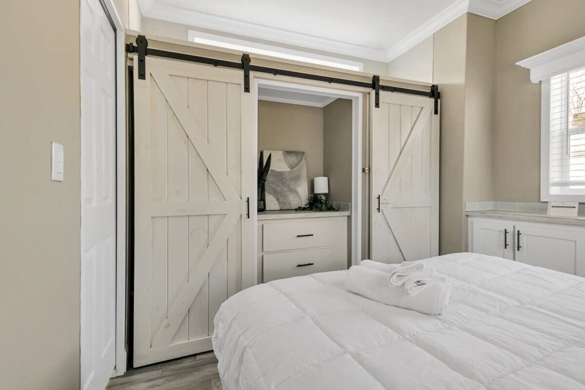 Un dormitorio con cama, cómoda y armario con puerta corredera estilo granero.