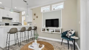 A modern kitchen with white cabinets, a built-in oven, and a dining area with a round wooden table. - Byrd 7 Nesting Nook (Owens Cross Roads)