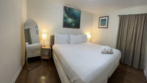 A hotel room with a large bed, two bedside lamps, a ceiling light, a painting on the wall, and a window with curtains. - 12th Ave The Bricks - Unit 4 (Birmingham)