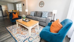Un salon comprenant un canapé, deux fauteuils, une table basse et un tapis à motifs.