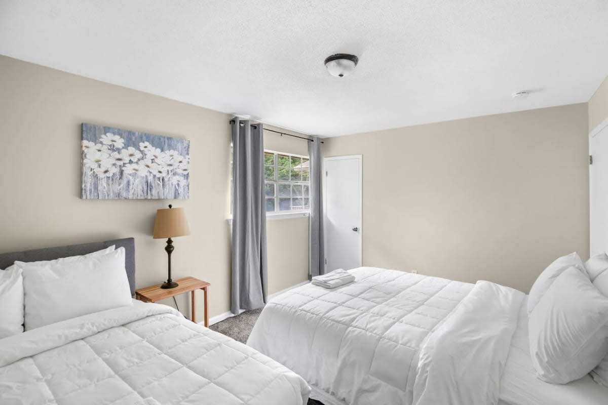 Een hotelkamer met twee bedden, een schilderij aan de muur, een lamp en een deur naar een balkon.