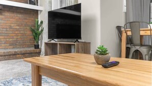 Ein Holztisch mit Fernbedienung und Topfpflanze.