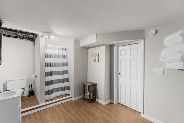 A bathroom with a shower curtain, a toilet, and a small table with a vase.