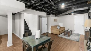 Een ruime woonkamer met een eettafel, bank en trap.