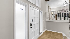 A hallway with white doors, a wooden floor, and a staircase with a railing. - Valley Lake Gem (Birmingham)