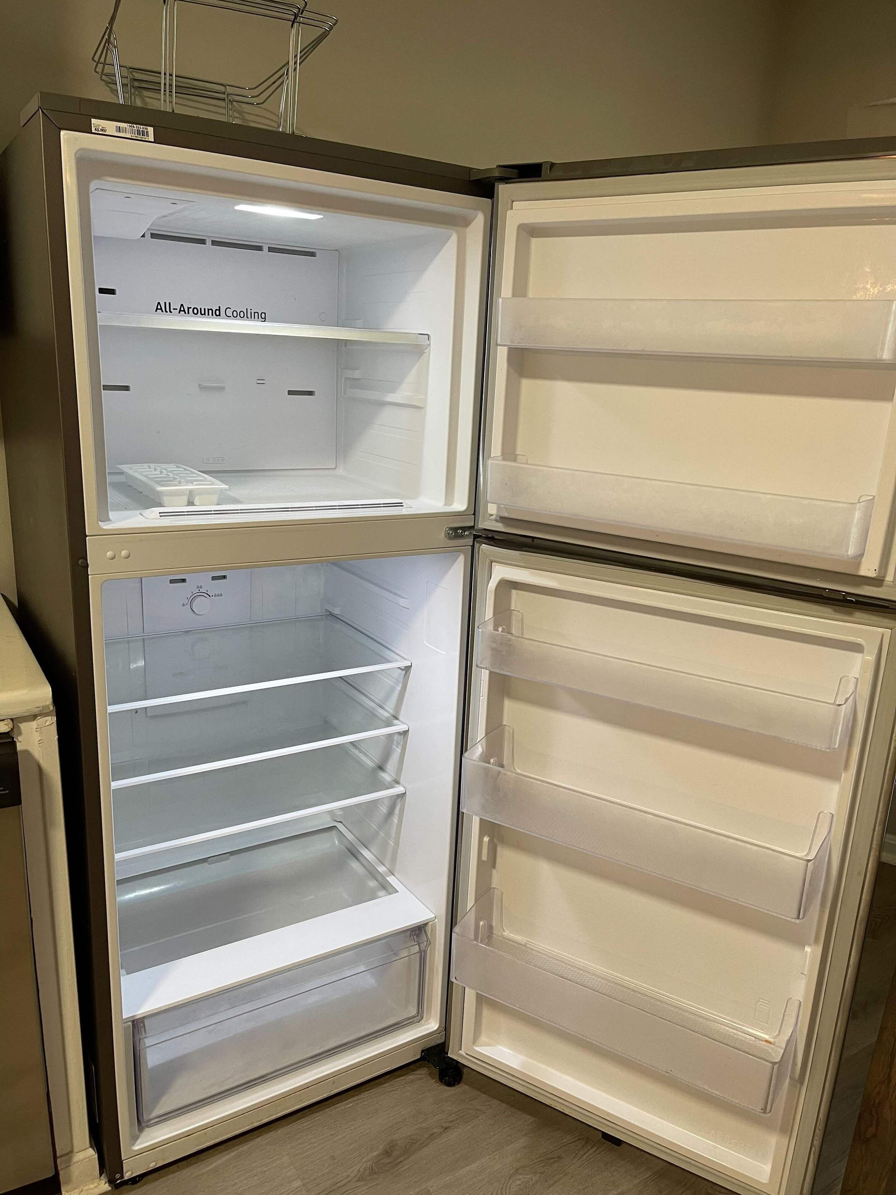 Un refrigerador de doble puerta con todas las repisas vacías, dispensador de agua y hielo, y una etiqueta que indica 'Enfriamiento Integral'.