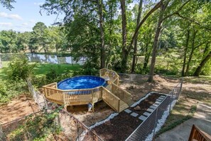 Un jardin avec une terrasse en bois, une piscine et une zone délimitée par une clôture.