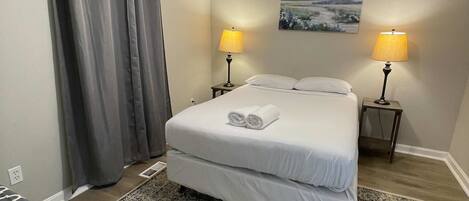 Camera d'albergo con un letto, due lampade sui comodini, una ventola a soffitto, un quadro appeso e un tappeto a motivi.