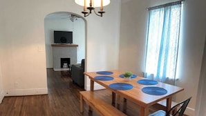 A dining area with a wooden table, blue placemats, and a bench. - 28th Street Historic at Norwood (Birmingham)