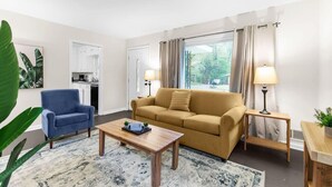 Un salon comprenant un canapé, un fauteuil, une table basse et donnant sur l’extérieur.