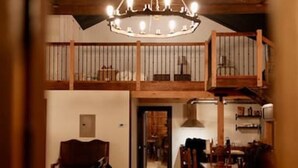 Un intérieur chaleureux avec un escalier en bois, un lustre et un coin repas.