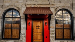 A building with a red door, two arched windows, and a stone facade. - The Scandinavian West Hall—Near Anthony Lakes! (North Powder)