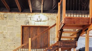 A wooden dining table with chairs, a staircase, and stone walls. - The Scandinavian East Hall—Near Anthony Lakes! (North Powder)