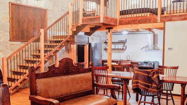 A spacious loft-style room with a wooden staircase, a dining area, and a kitchen. - The Scandinavian East Hall—Near Anthony Lakes! (North Powder)